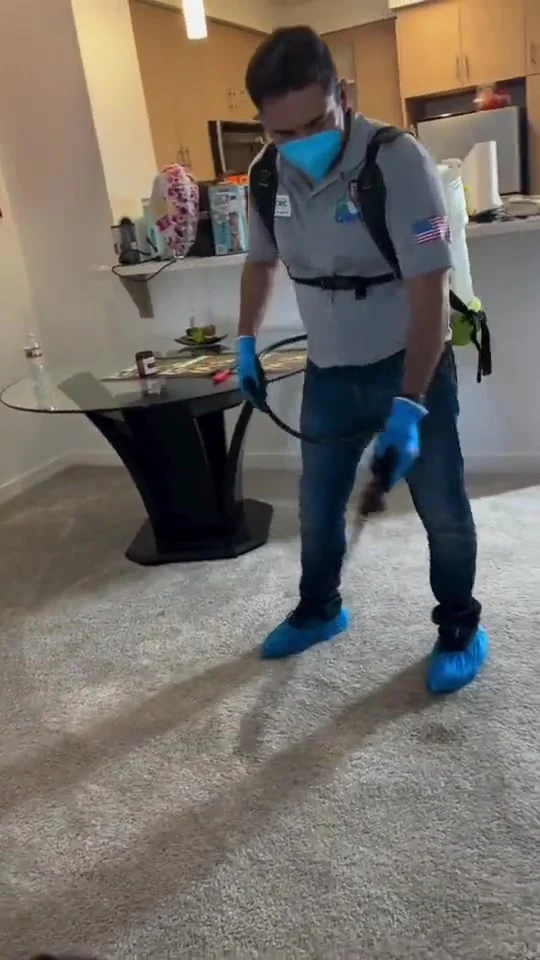 Dr. Carpet technician applying a preconditioning pre-spray to carpet with a backpack sprayer