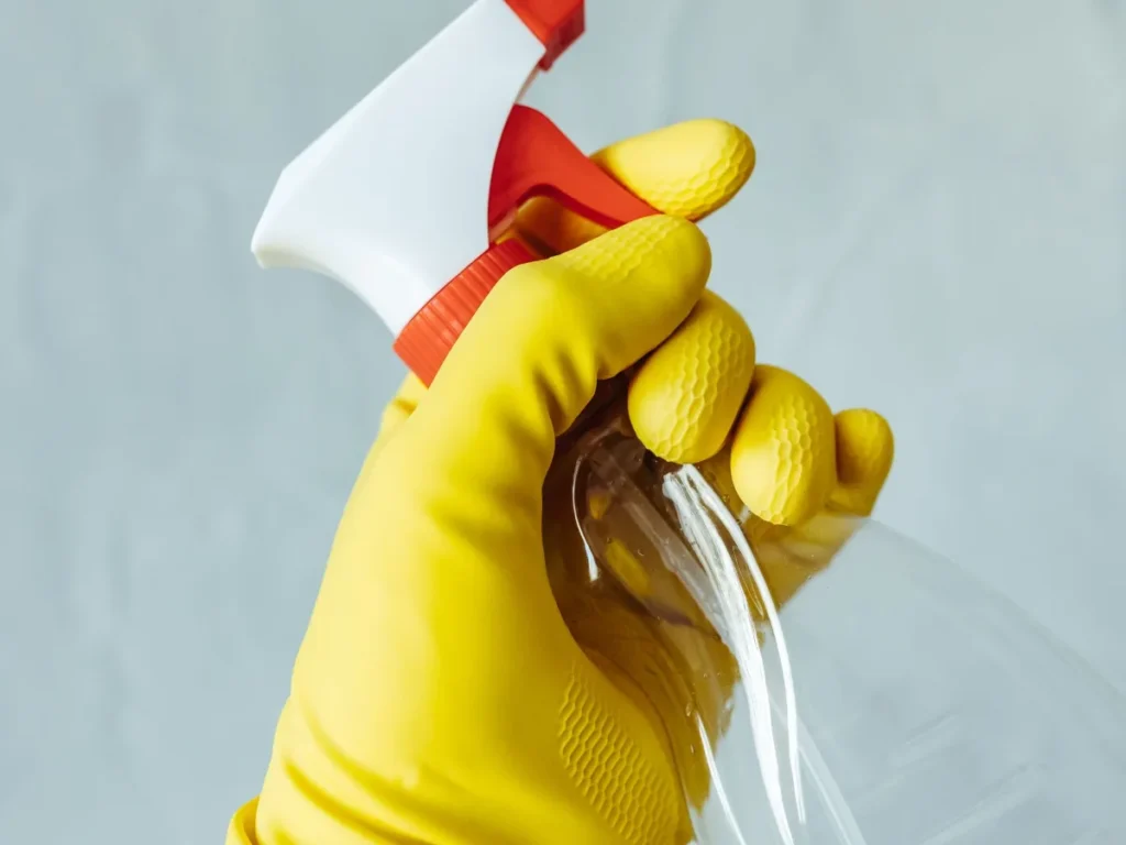 Gloved hand holding a spray bottle for a spot treatment
