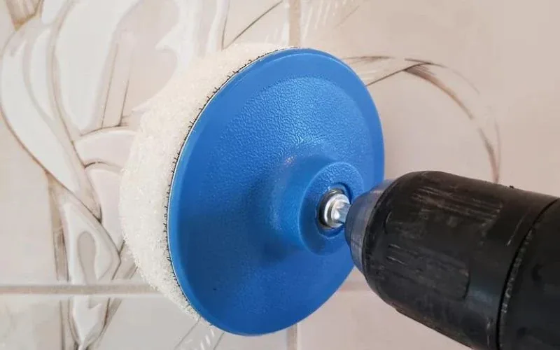 Rotary scrub brush cleaning grout lines on bathroom wall tile