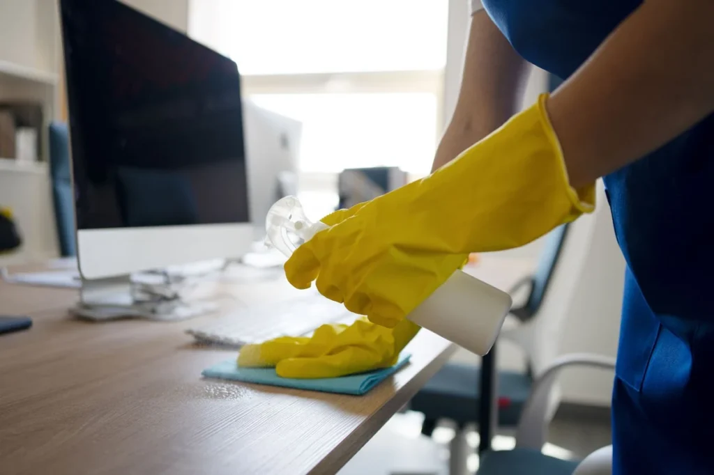 Office desk being wiped down during after-hours cleaning