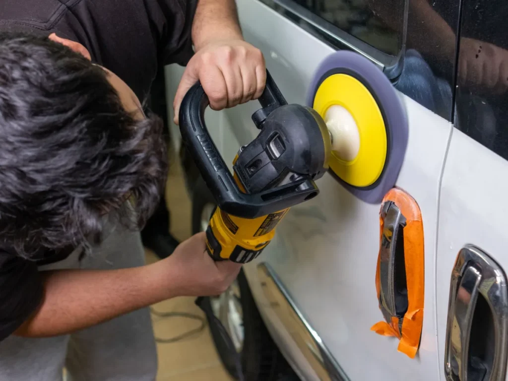 Detailer polishing a car door with a machine polisher during a full detail