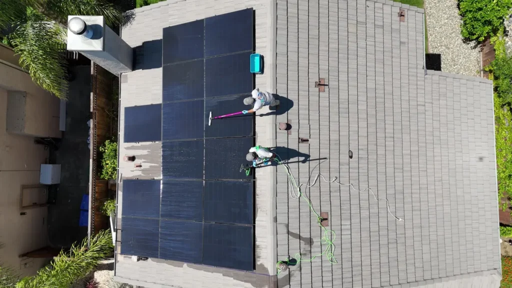 Top view of two technicians cleaning a solar array on a tile roof