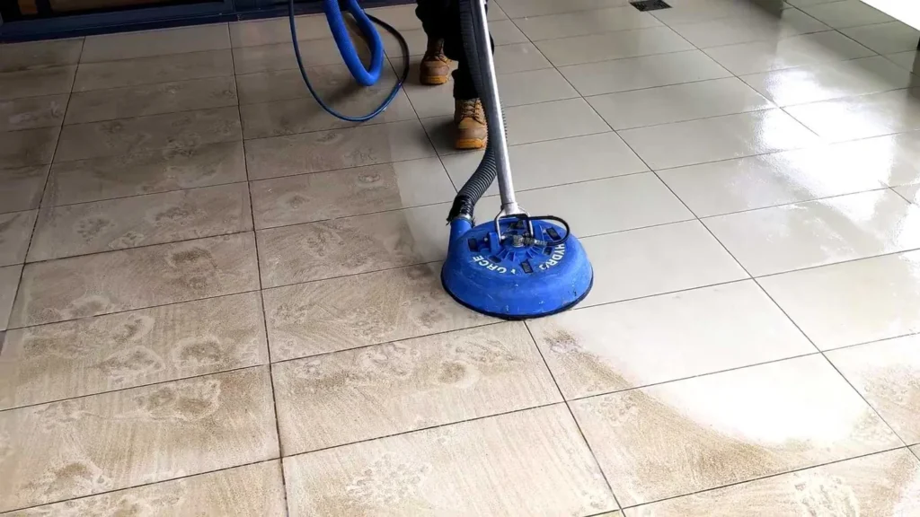 Tile floor half cleaned with a professional spinner tool, showing the before and after line