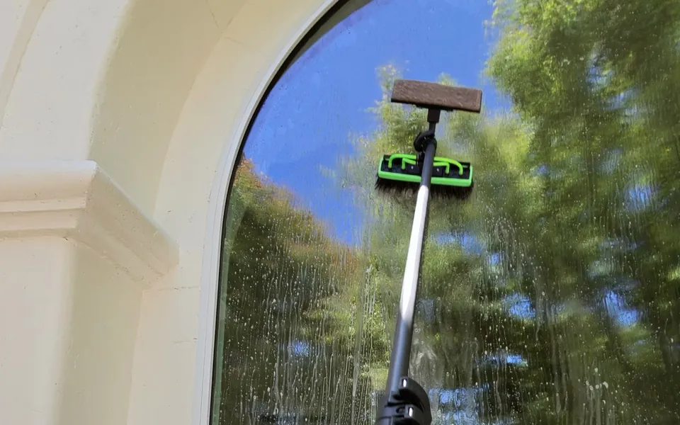 Dr. Carpet technician cleaning an arched window with a water-fed pole and pure water in Walnut Creek, CA